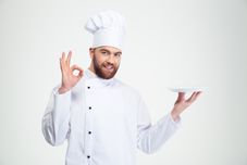 Portrait of a man chef showing ok sign and empty plate isolated on a w